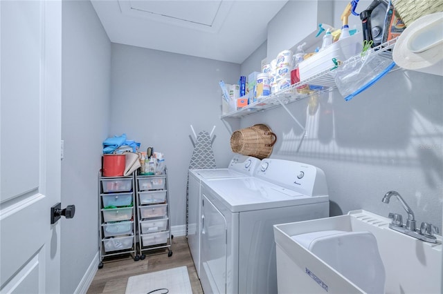 clothes washing area with light hardwood / wood-style floors, independent washer and dryer, and sink