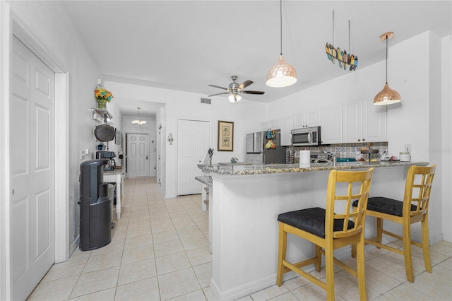 kitchen featuring white cabinets, kitchen peninsula, stainless steel appliances, backsplash, and ceiling fan