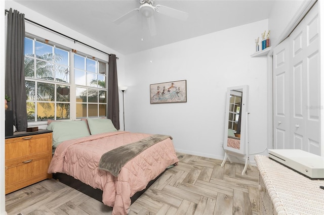 bedroom with light parquet flooring, ceiling fan, and a closet