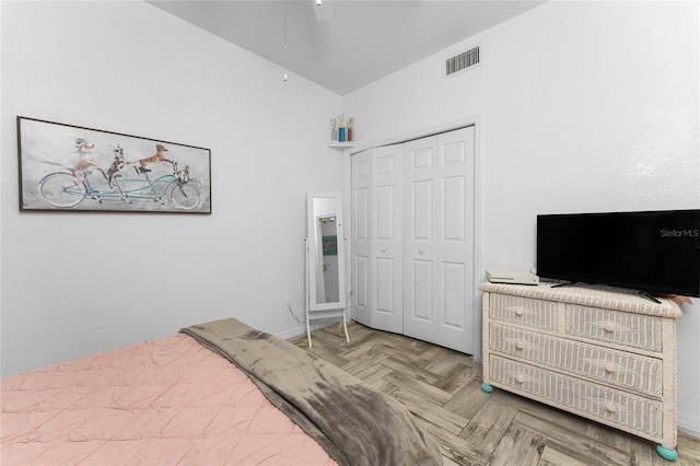 bedroom with parquet floors, ceiling fan, and a closet