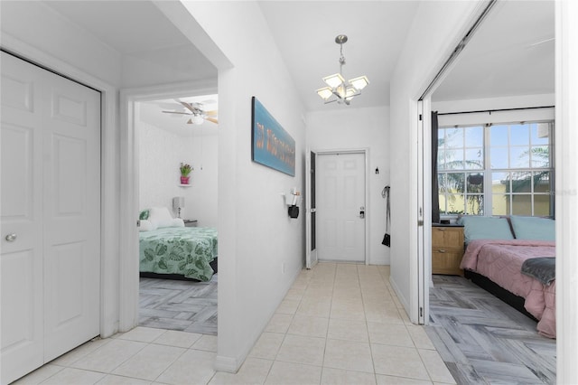 foyer with ceiling fan with notable chandelier, lofted ceiling, and light parquet floors