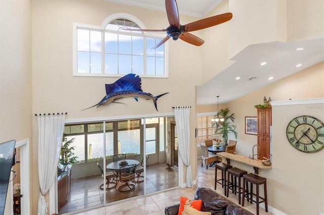 tiled living room with a high ceiling, ornamental molding, and ceiling fan