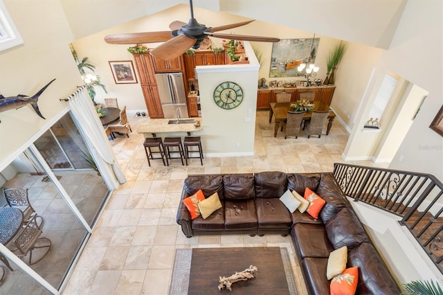 living room featuring high vaulted ceiling and ceiling fan with notable chandelier