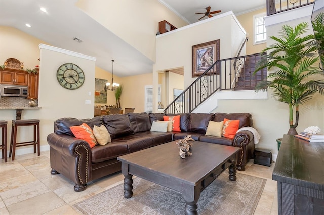 living room featuring ceiling fan with notable chandelier, ornamental molding, and a high ceiling