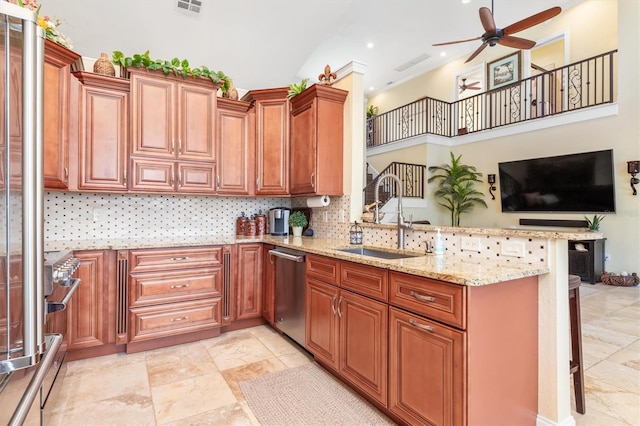 kitchen featuring sink, a breakfast bar area, stainless steel appliances, light stone counters, and kitchen peninsula