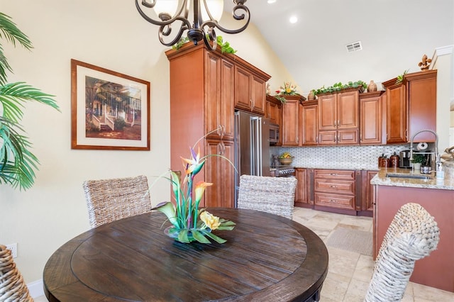 dining space featuring light tile patterned flooring, a notable chandelier, and high vaulted ceiling