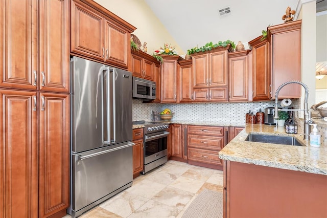 kitchen with appliances with stainless steel finishes, light stone counters, tasteful backsplash, lofted ceiling, and sink