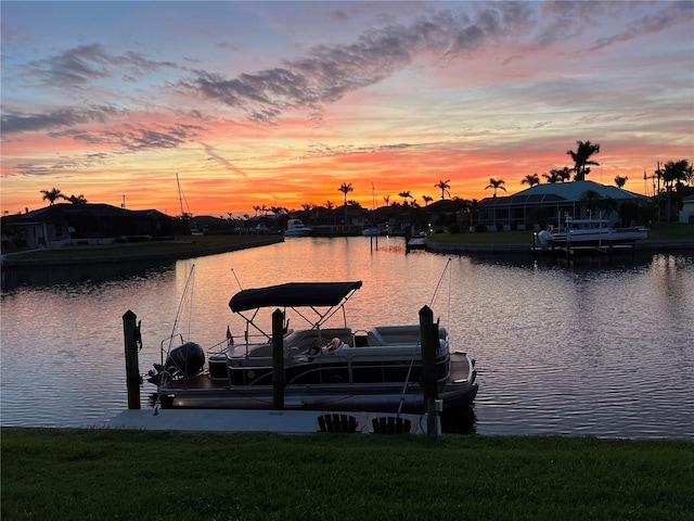 view of dock with a lawn and a water view