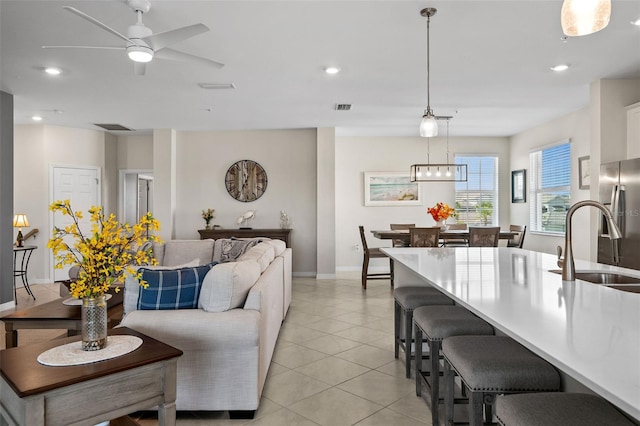 tiled living room featuring ceiling fan and sink