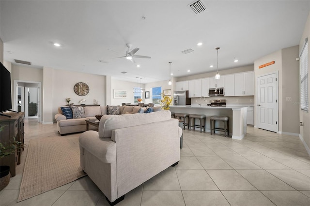 living room featuring light tile patterned flooring, sink, and ceiling fan