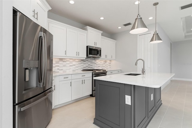 kitchen featuring sink, white cabinetry, a center island with sink, appliances with stainless steel finishes, and decorative light fixtures