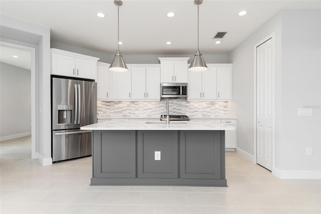 kitchen featuring appliances with stainless steel finishes, decorative backsplash, white cabinetry, an island with sink, and decorative light fixtures