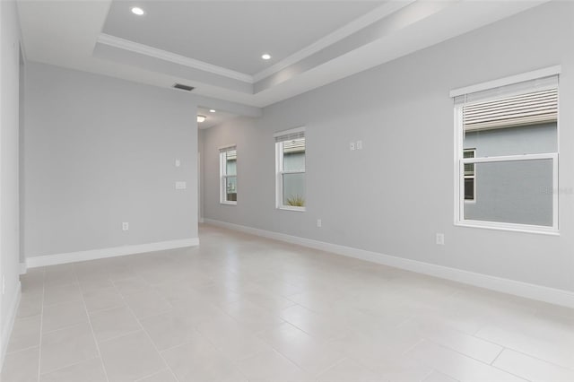 unfurnished room with a raised ceiling, light tile patterned floors, and crown molding