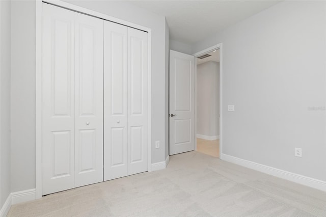 unfurnished bedroom featuring light colored carpet and a closet