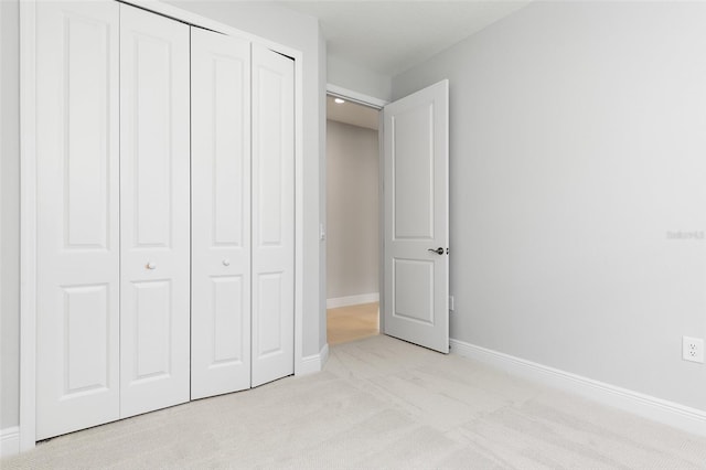 unfurnished bedroom featuring light carpet and a closet