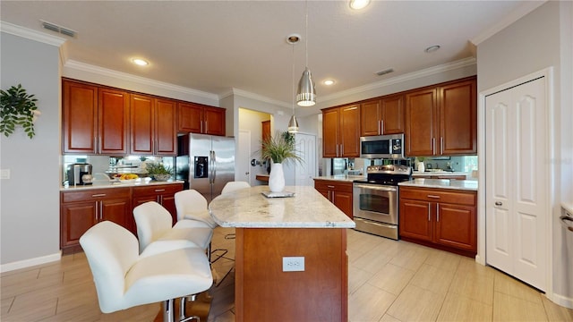 kitchen featuring crown molding, a center island, stainless steel appliances, and decorative light fixtures