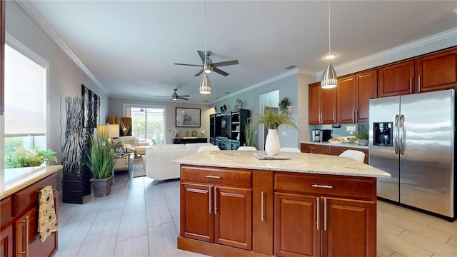 kitchen with pendant lighting, stainless steel fridge with ice dispenser, a kitchen island, light stone countertops, and ceiling fan