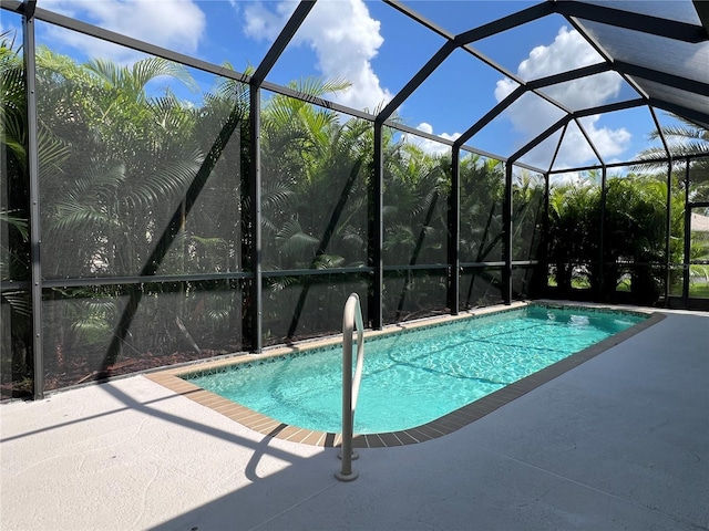 view of pool with glass enclosure and a patio area