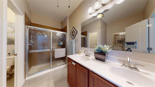 bathroom featuring a shower with door, toilet, and vanity