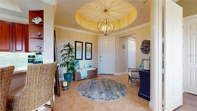 tiled entrance foyer with crown molding, a tray ceiling, and an inviting chandelier