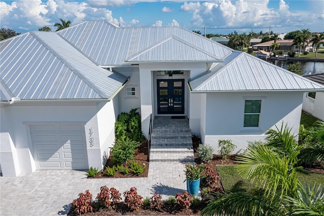 view of front of house featuring a water view, a garage, and french doors