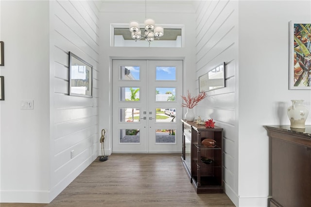 foyer featuring a towering ceiling, hardwood / wood-style floors, french doors, and a notable chandelier