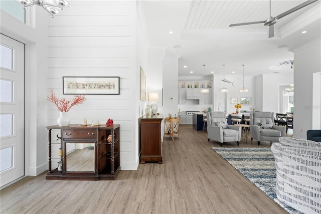 living room with ceiling fan, ornamental molding, light hardwood / wood-style flooring, and a high ceiling