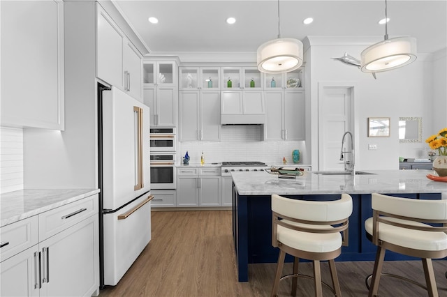 kitchen with sink, white cabinets, stainless steel appliances, decorative light fixtures, and light stone countertops