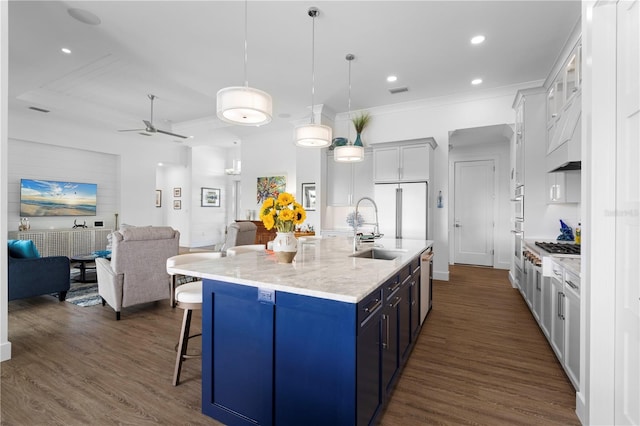 kitchen featuring hanging light fixtures, white cabinetry, sink, and an island with sink