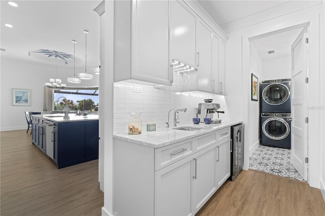 kitchen with white cabinets, stacked washer and dryer, wine cooler, and sink