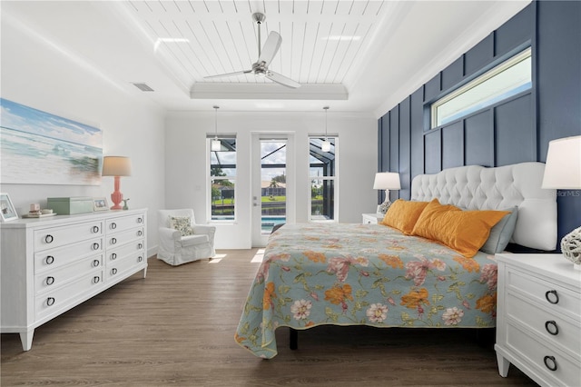 bedroom with a tray ceiling, ceiling fan, dark wood-type flooring, and access to exterior