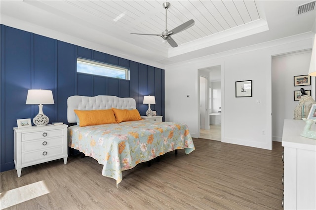 bedroom with a raised ceiling, ornamental molding, hardwood / wood-style floors, and ceiling fan