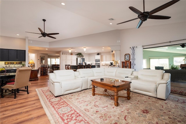 living room featuring light hardwood / wood-style flooring, vaulted ceiling, and ceiling fan