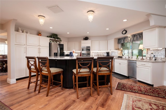 kitchen featuring stainless steel appliances, white cabinetry, and a center island