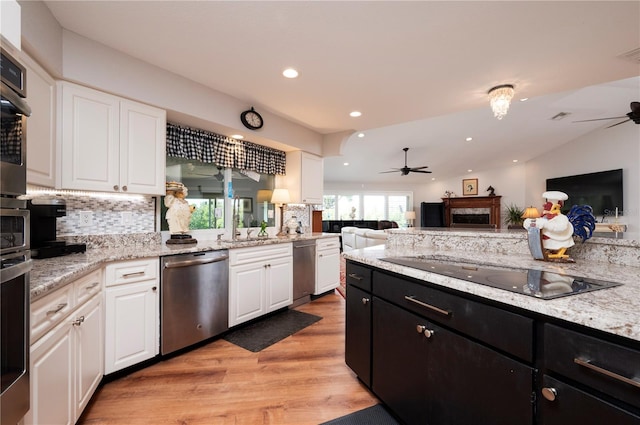 kitchen with appliances with stainless steel finishes, light hardwood / wood-style floors, white cabinetry, vaulted ceiling, and ceiling fan