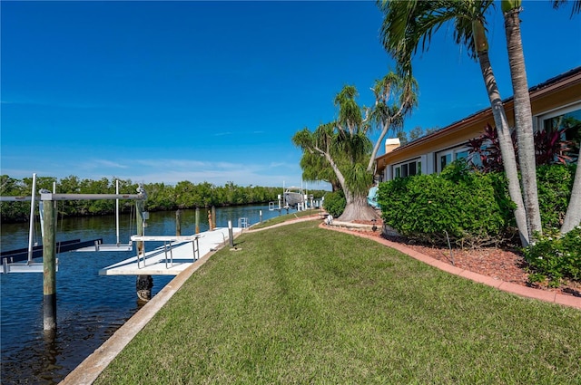 view of dock with a lawn and a water view