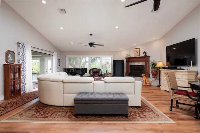 living room featuring ceiling fan, lofted ceiling, a fireplace, and light hardwood / wood-style floors