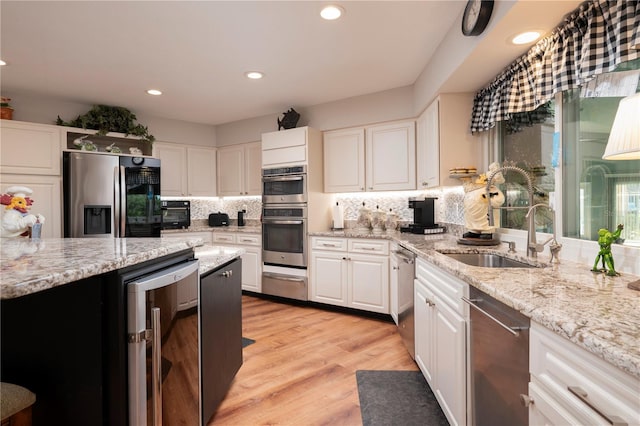 kitchen featuring white cabinets, beverage cooler, stainless steel appliances, and light hardwood / wood-style floors