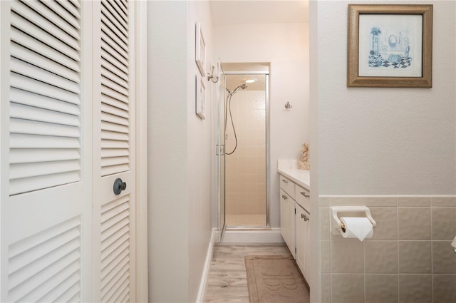 bathroom with hardwood / wood-style flooring, a shower with door, and vanity