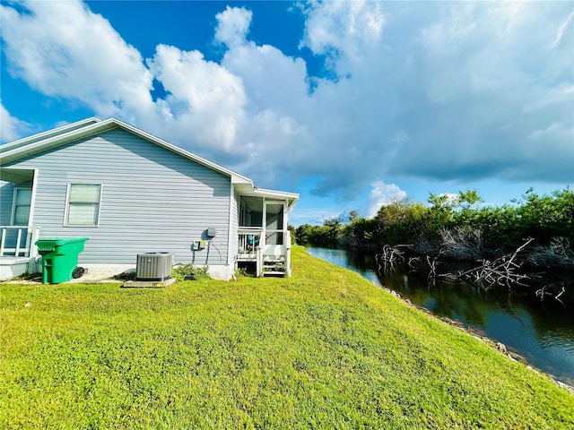 view of side of home with cooling unit, a lawn, and a water view