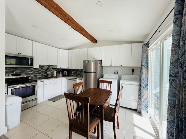 kitchen with lofted ceiling with beams, tasteful backsplash, white cabinetry, appliances with stainless steel finishes, and independent washer and dryer