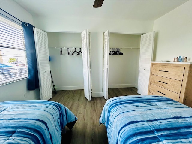 bedroom with ceiling fan, multiple closets, and dark hardwood / wood-style flooring