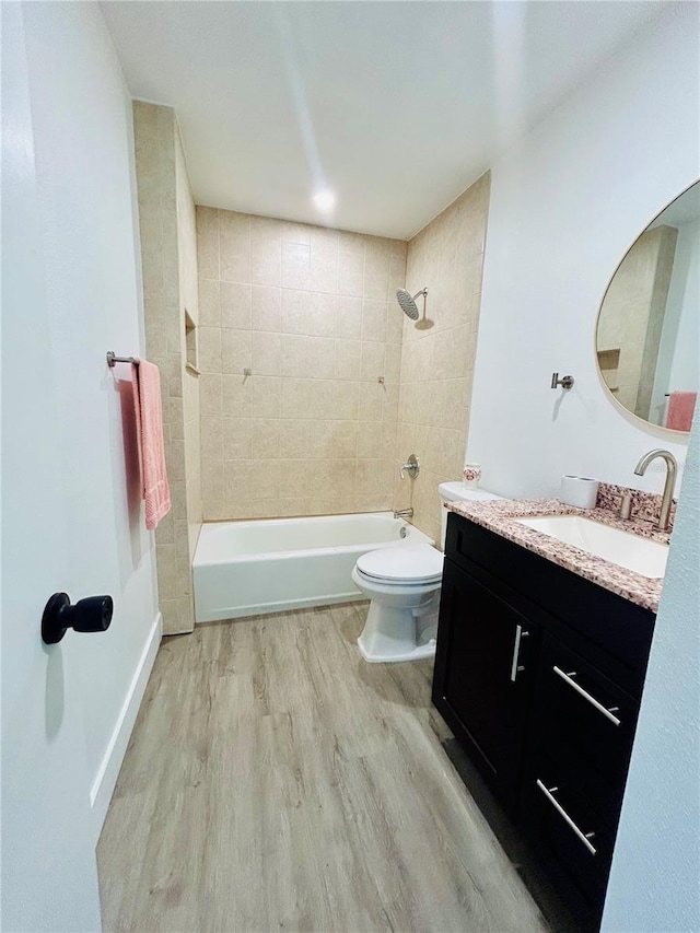 full bathroom with wood-type flooring, vanity, tiled shower / bath combo, and toilet