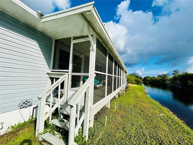 view of side of home with a sunroom and a water view