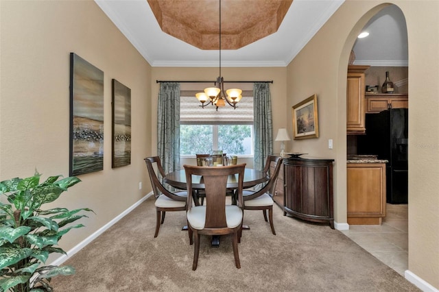 carpeted dining area with crown molding, a tray ceiling, and a chandelier