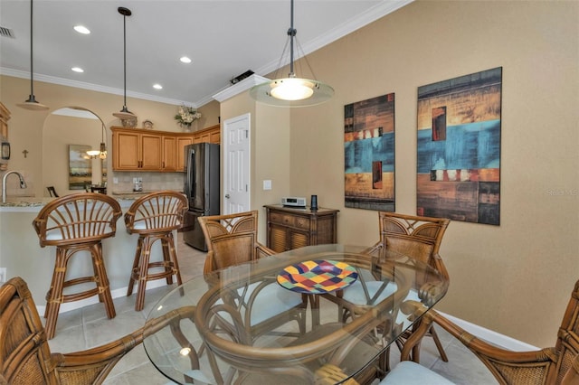 dining room featuring light tile patterned flooring, sink, and crown molding