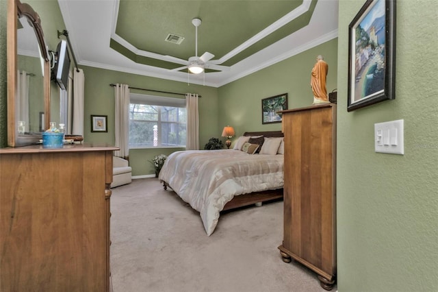 carpeted bedroom with a tray ceiling, ceiling fan, and crown molding