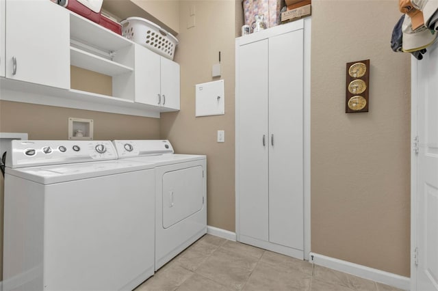 clothes washing area with light tile patterned flooring, cabinets, and washing machine and clothes dryer