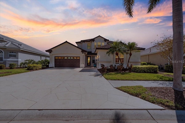 view of front of house featuring a garage, concrete driveway, a tile roof, a front lawn, and stucco siding