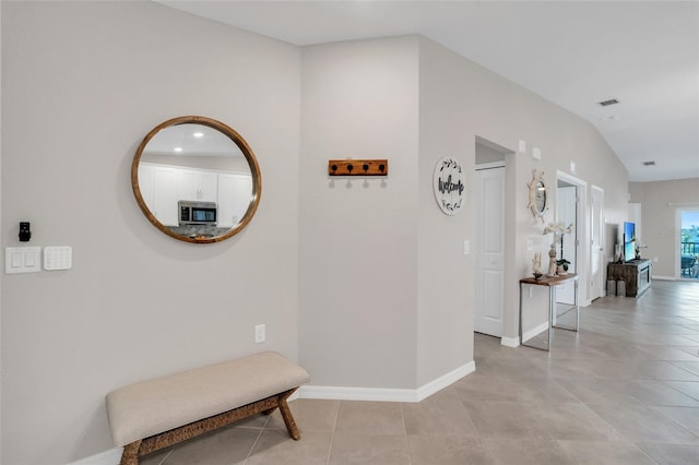 corridor with light tile patterned floors and vaulted ceiling